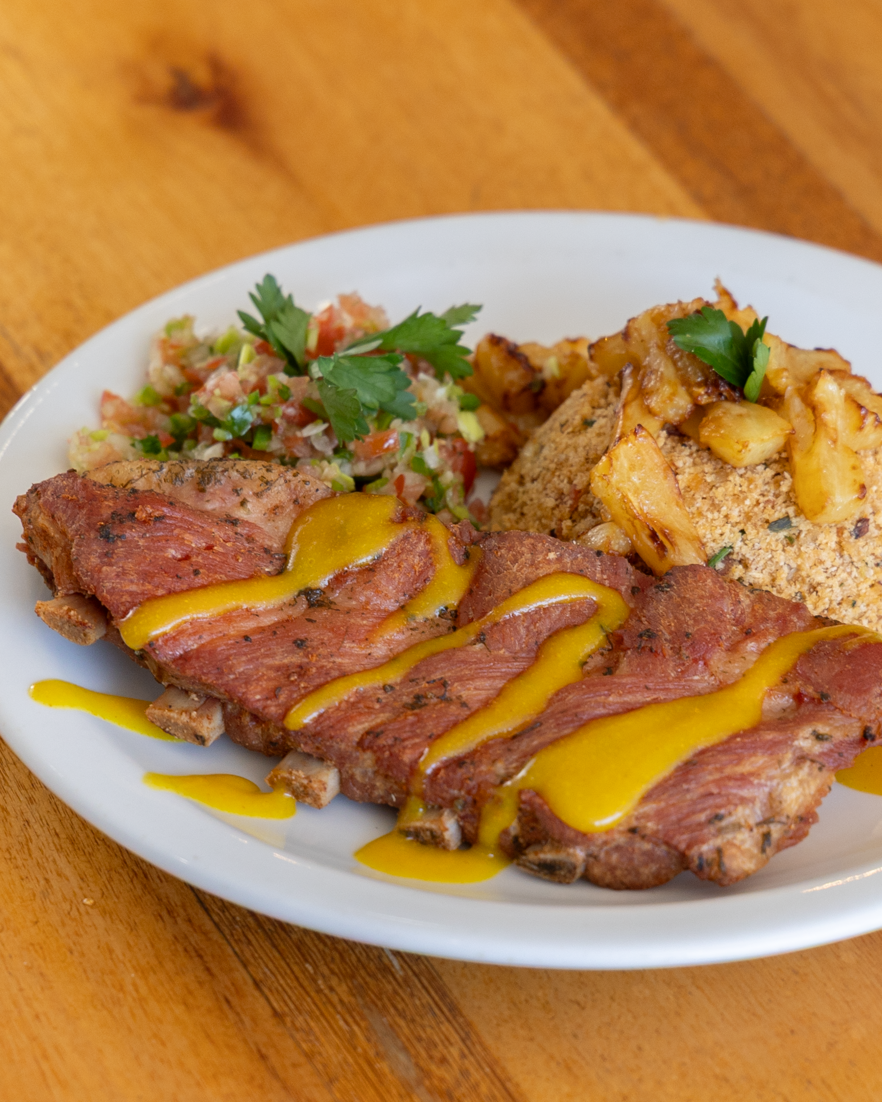 Costela de porco acompanhada de farofa de abacaxi com vinagrete. - Foto: Olho Gordo